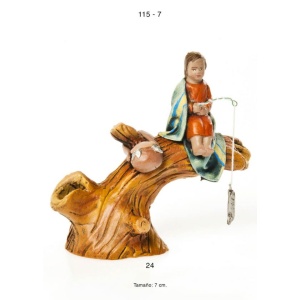 Niño sentado en tronco pescando.